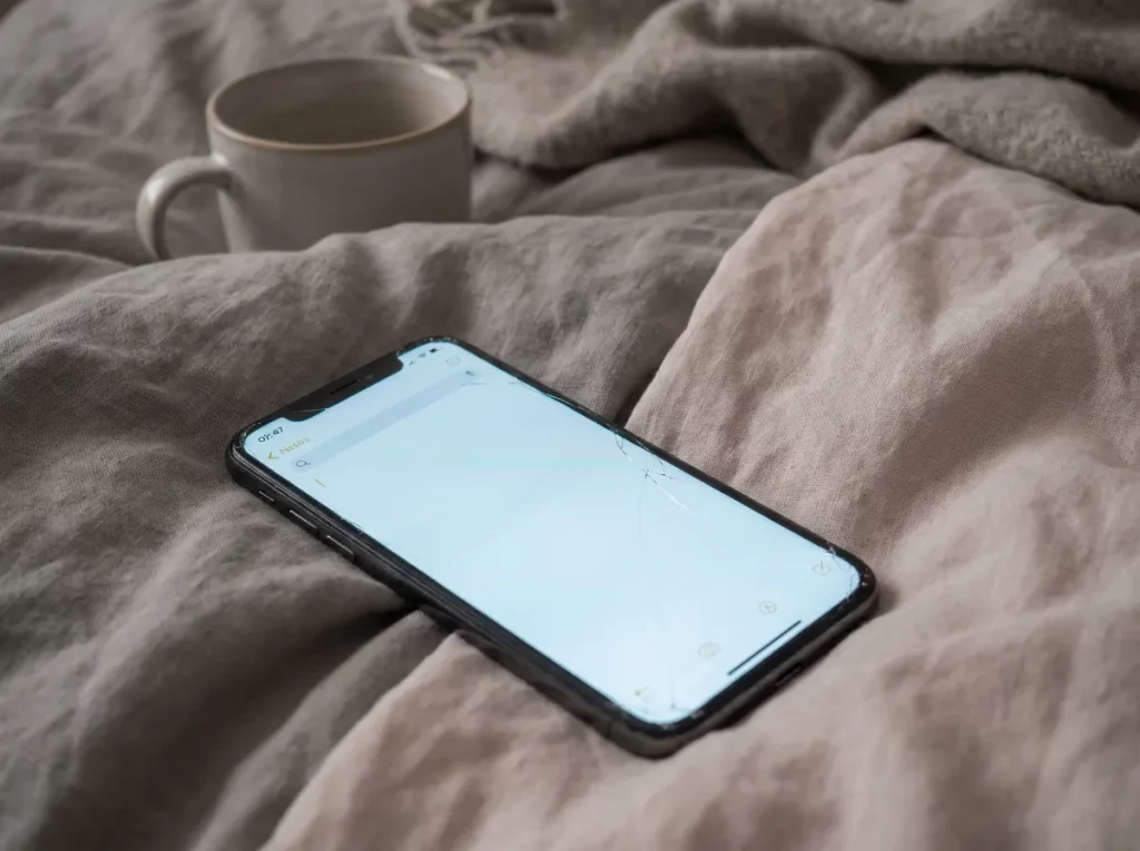Smartphone im Bett als Symbol für kreisende Gedanken nach der Arbeit